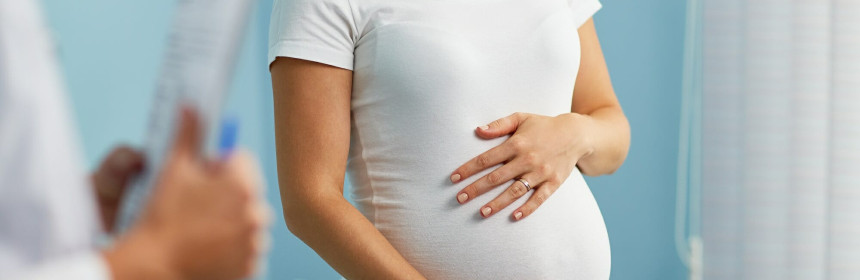 pregnant-woman-with-hands-on-stomach-talking-to-obstetrician_BnOL_ByJM